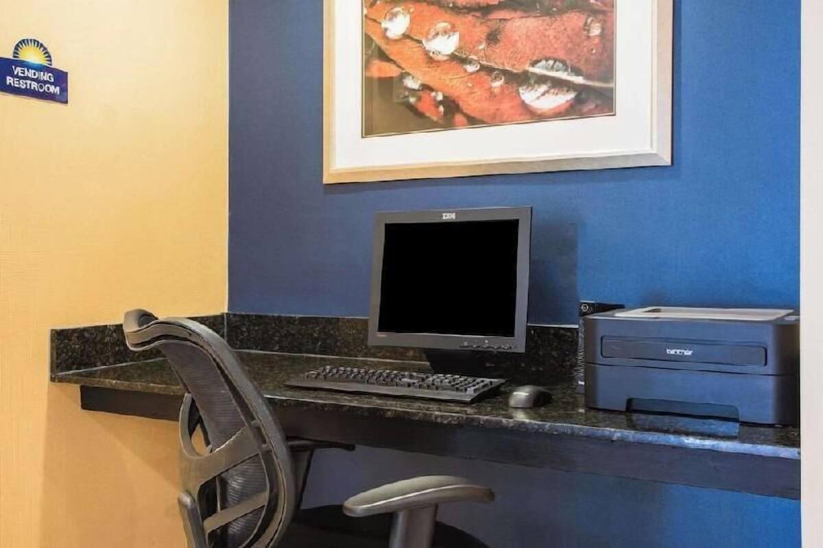 A reception desk with a computer, printer, and a chair.