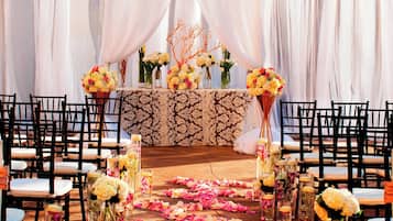 A wedding ceremony setup with a floral arrangement, chairs, and a table.