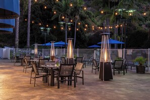 An outdoor patio with tables and chairs, string lights, and umbrellas. - Sheraton Mission Valley San Diego Hotel (San Diego)