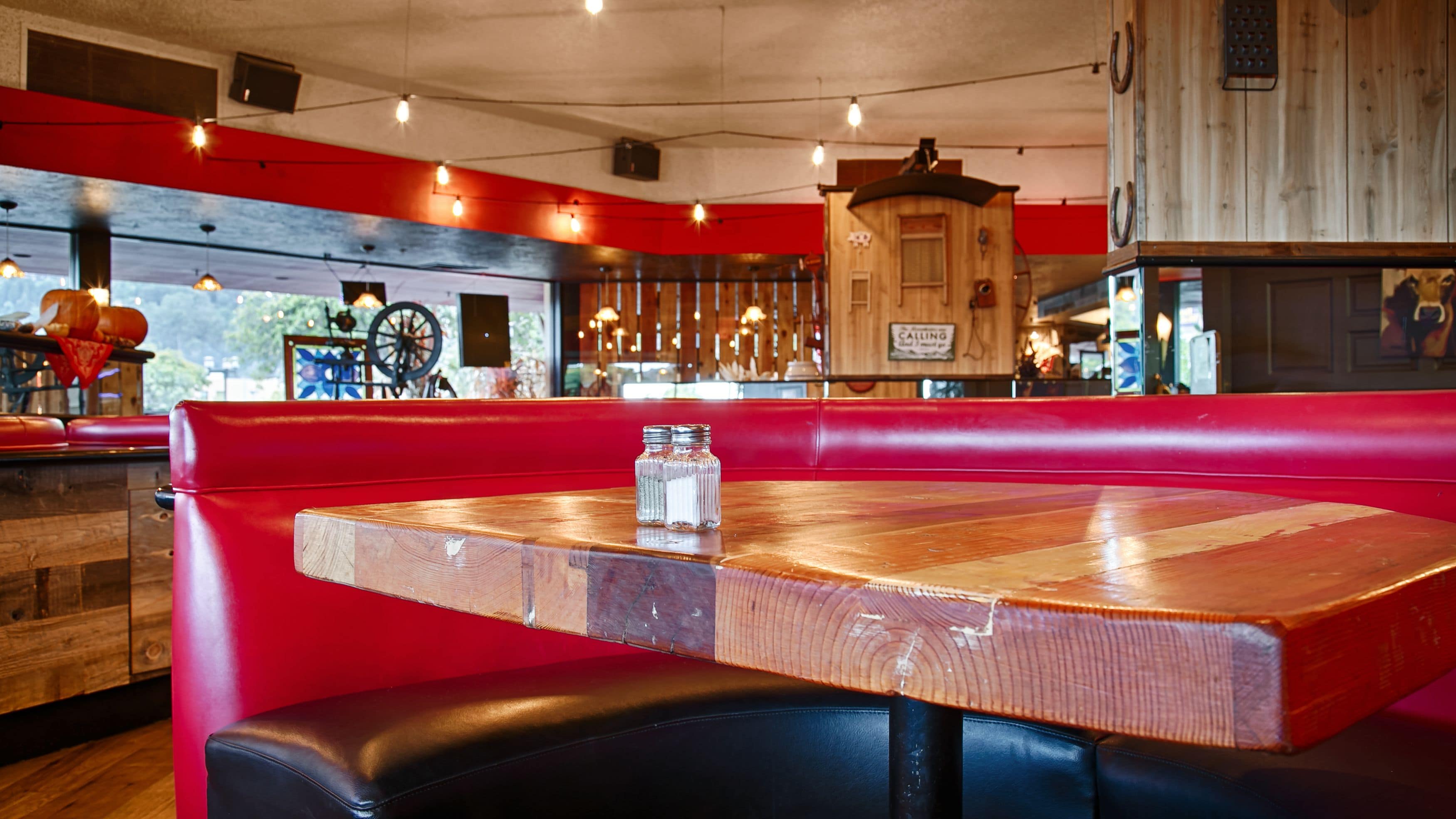 A restaurant interior with a wooden table and red seating.