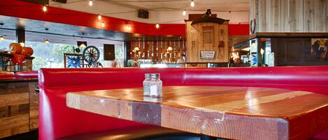 A restaurant interior with a wooden table and red seating.
