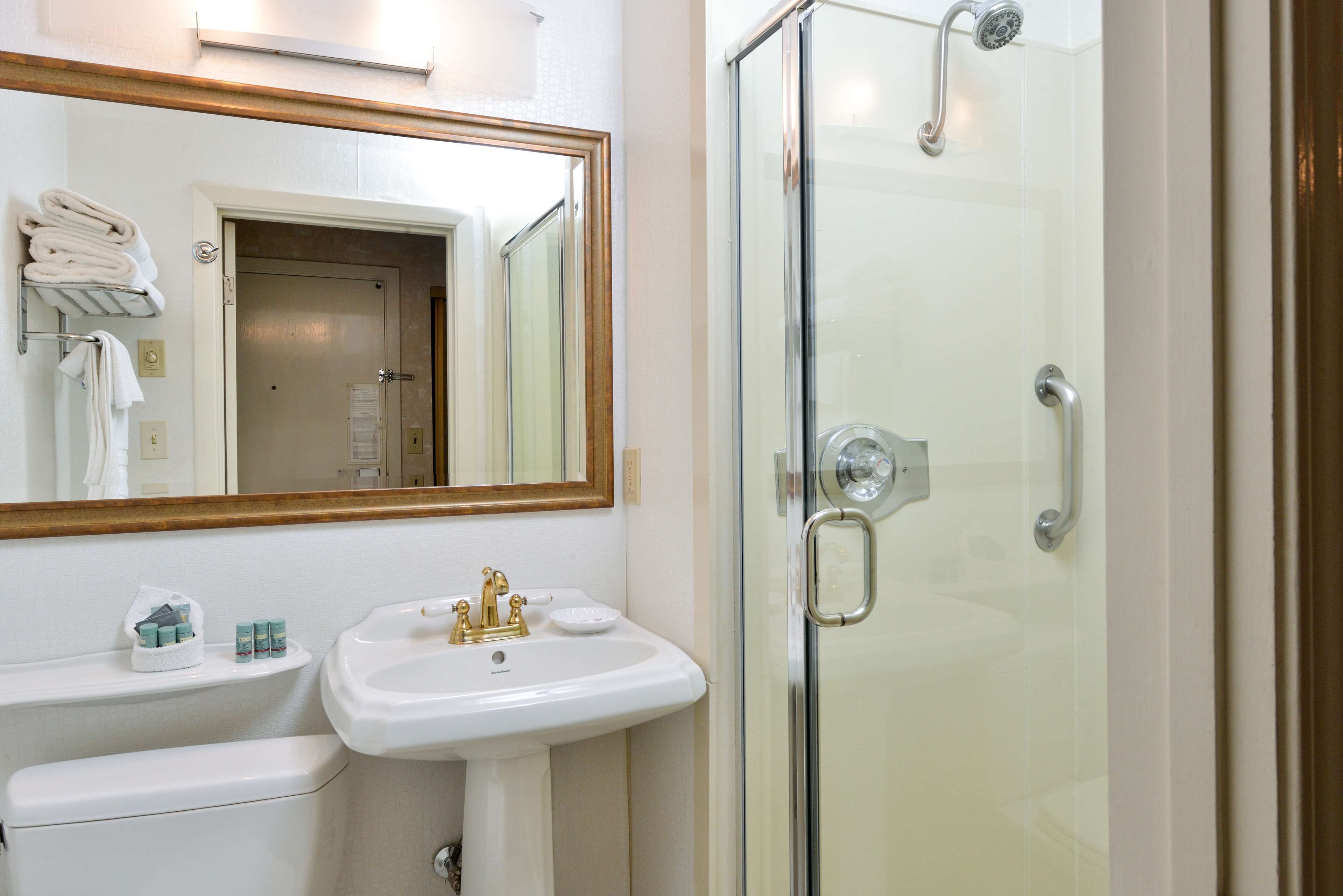 Un baño con lavamanos, espejo y cabina de ducha de vidrio.