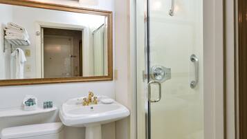 Un baño con lavamanos, espejo y cabina de ducha de vidrio.