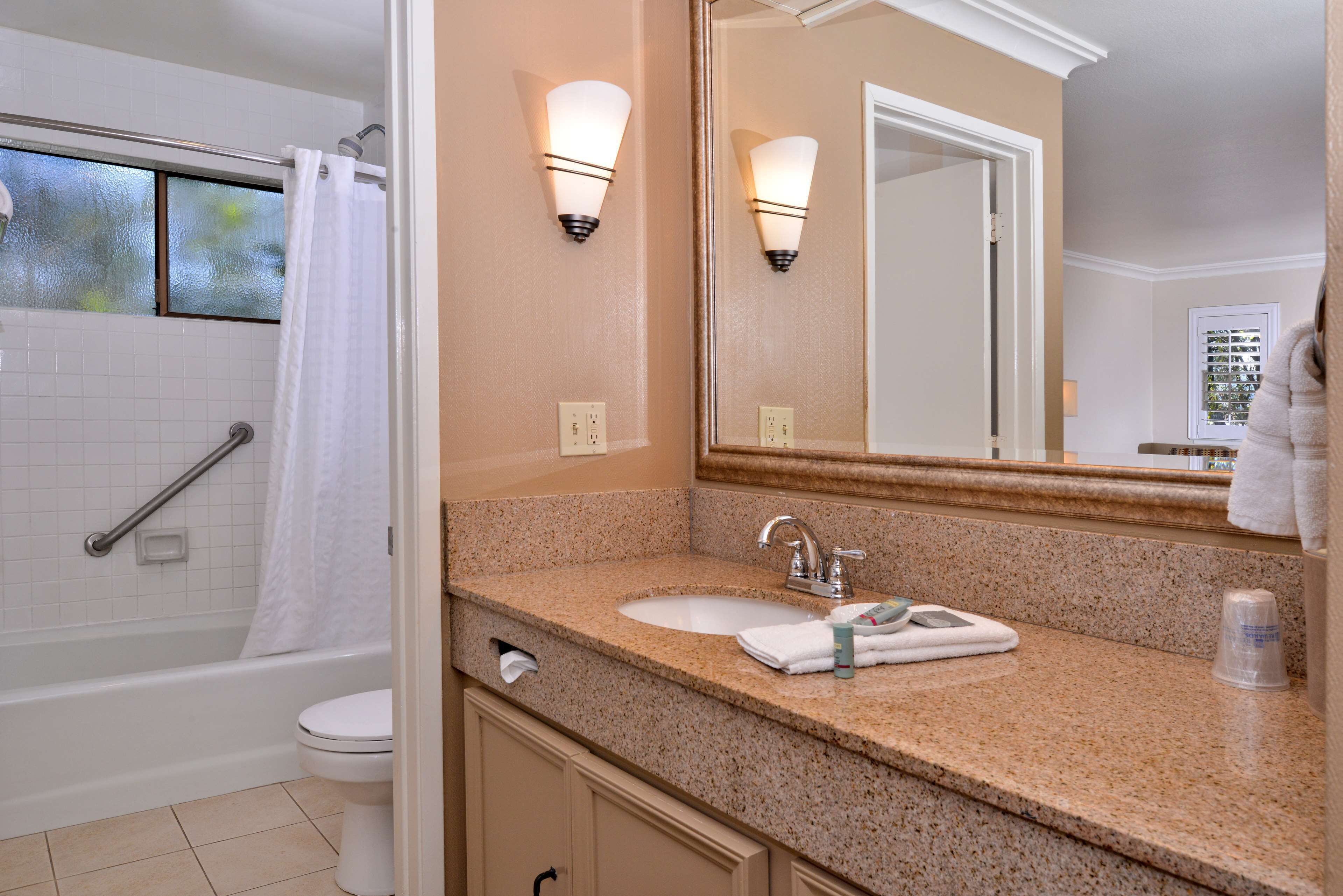 A bathroom with a bathtub, toilet, sink, and a large mirror.