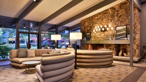 A modern lobby with a stone wall, a fireplace, and a seating area with a sofa and armchairs. - Best Western Corte Madera Inn (Corte Madera)