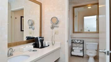 A bathroom with two sinks, a coffee maker, a towel rack, and a toilet.