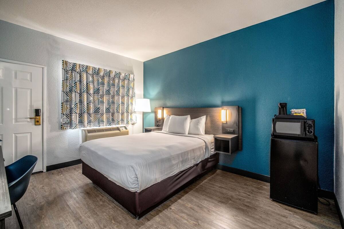 Ein Hotelzimmer mit Bett, Nachttischen, Schreibtisch und Stuhl.