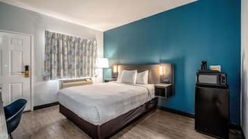 A hotel room with a bed, bedside tables, a desk, and a chair.