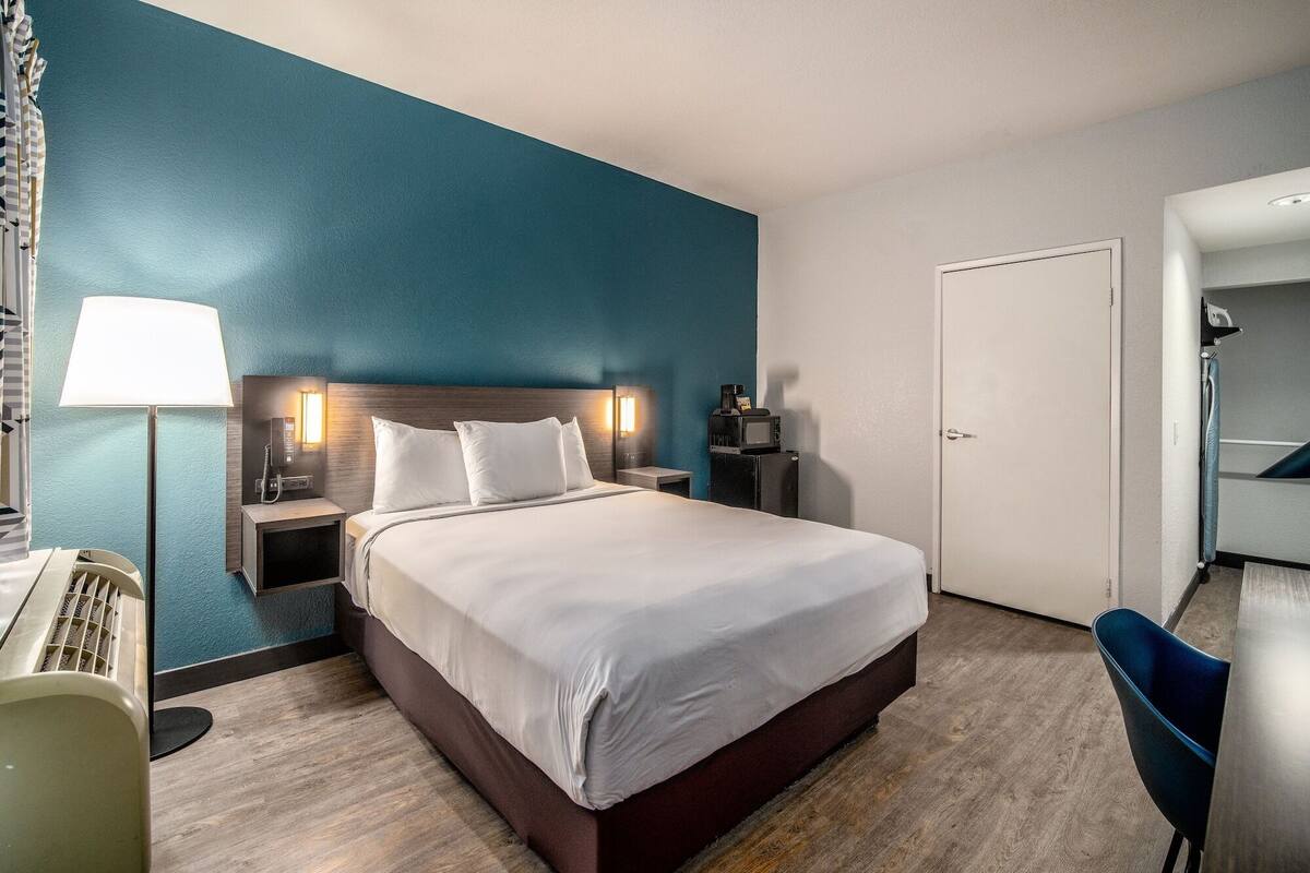 Ein Hotelzimmer mit einem Bett, Nachttischen, einer Lampe, einer Mikrowelle und einer Tür.