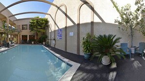 A pool area with a clear view of the pool, surrounding chairs, and potted plants. - Studio 6 Suites Lawndale, CA – South Bay (Lawndale)