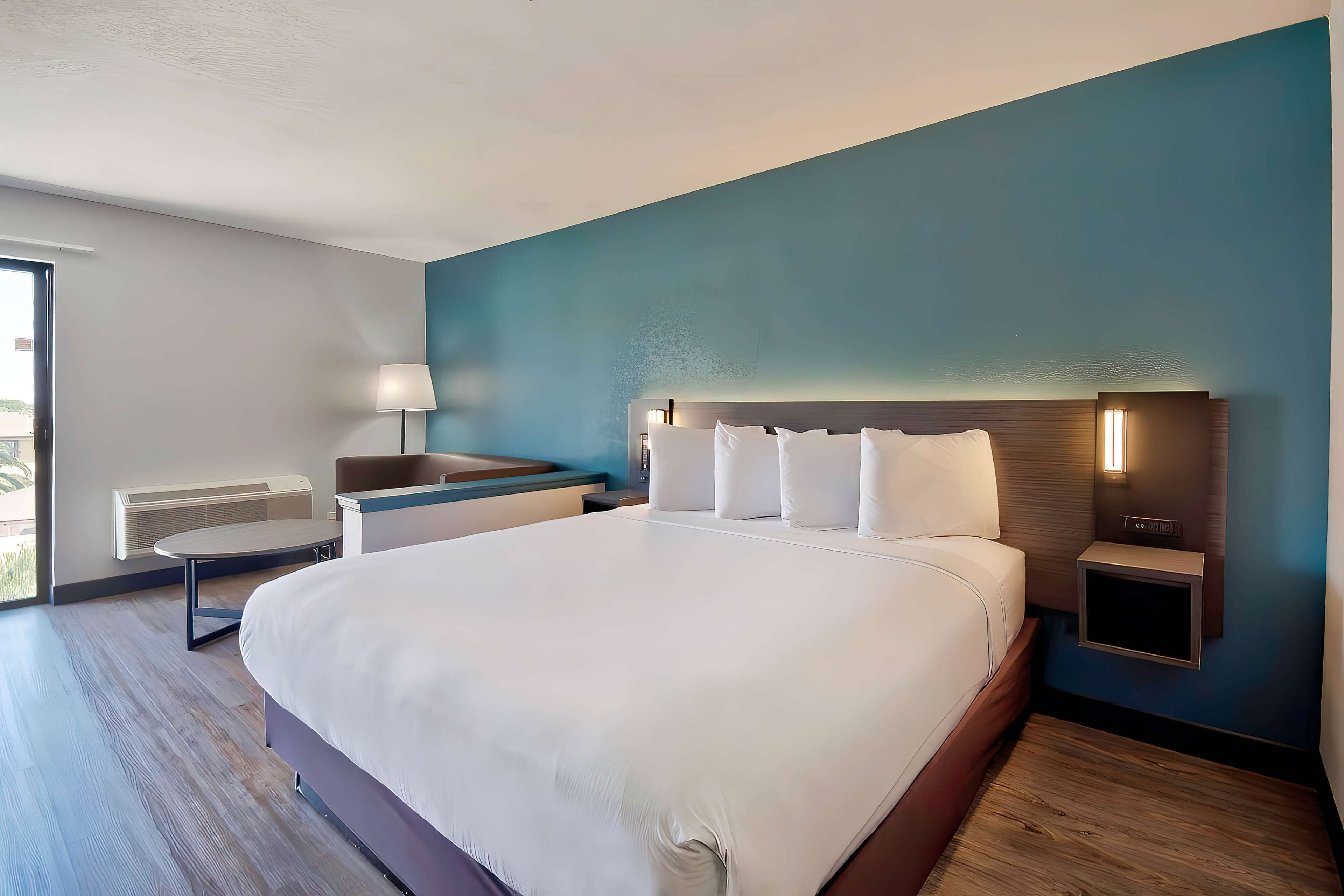 Ein modernes Hotelzimmer mit einem großen Bett, Nachttischen, einem Schreibtisch und einer Lampe.