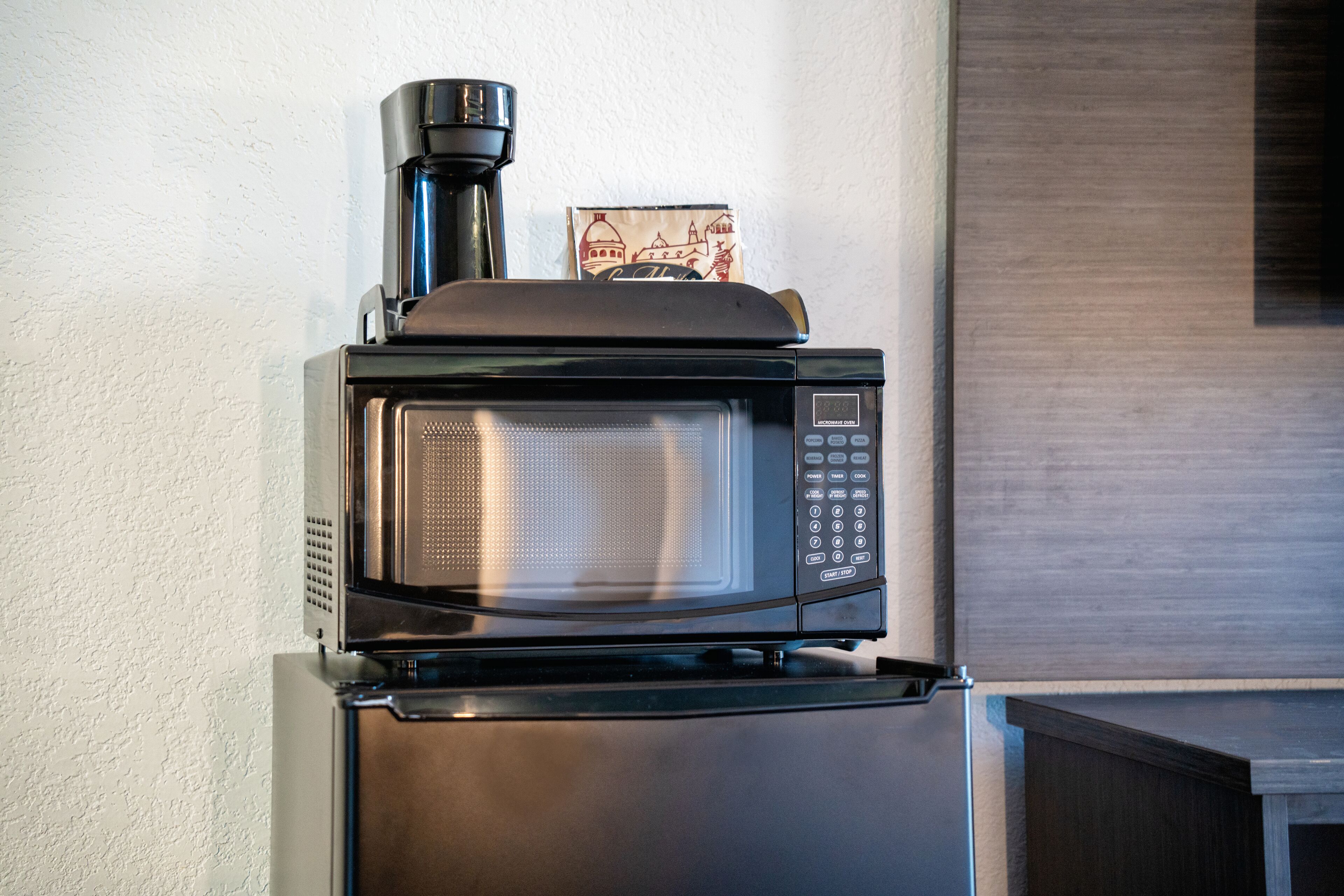 Een kleine keukenindeling met een magnetron en koffiezetapparaat bovenop een koelkast.