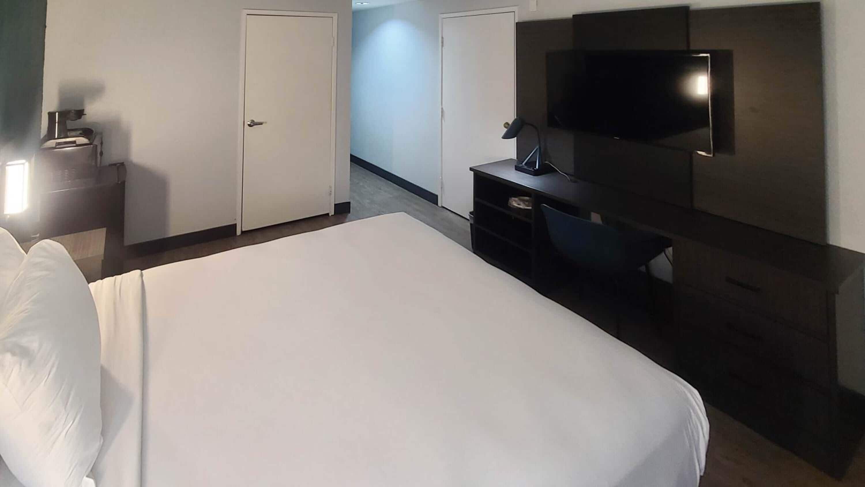Een hotelkamer met een bed, een bureau, een stoel, een televisie en een kledingkast.
