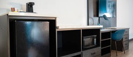 A modern kitchen with a refrigerator, microwave, and a coffee maker on the countertop.