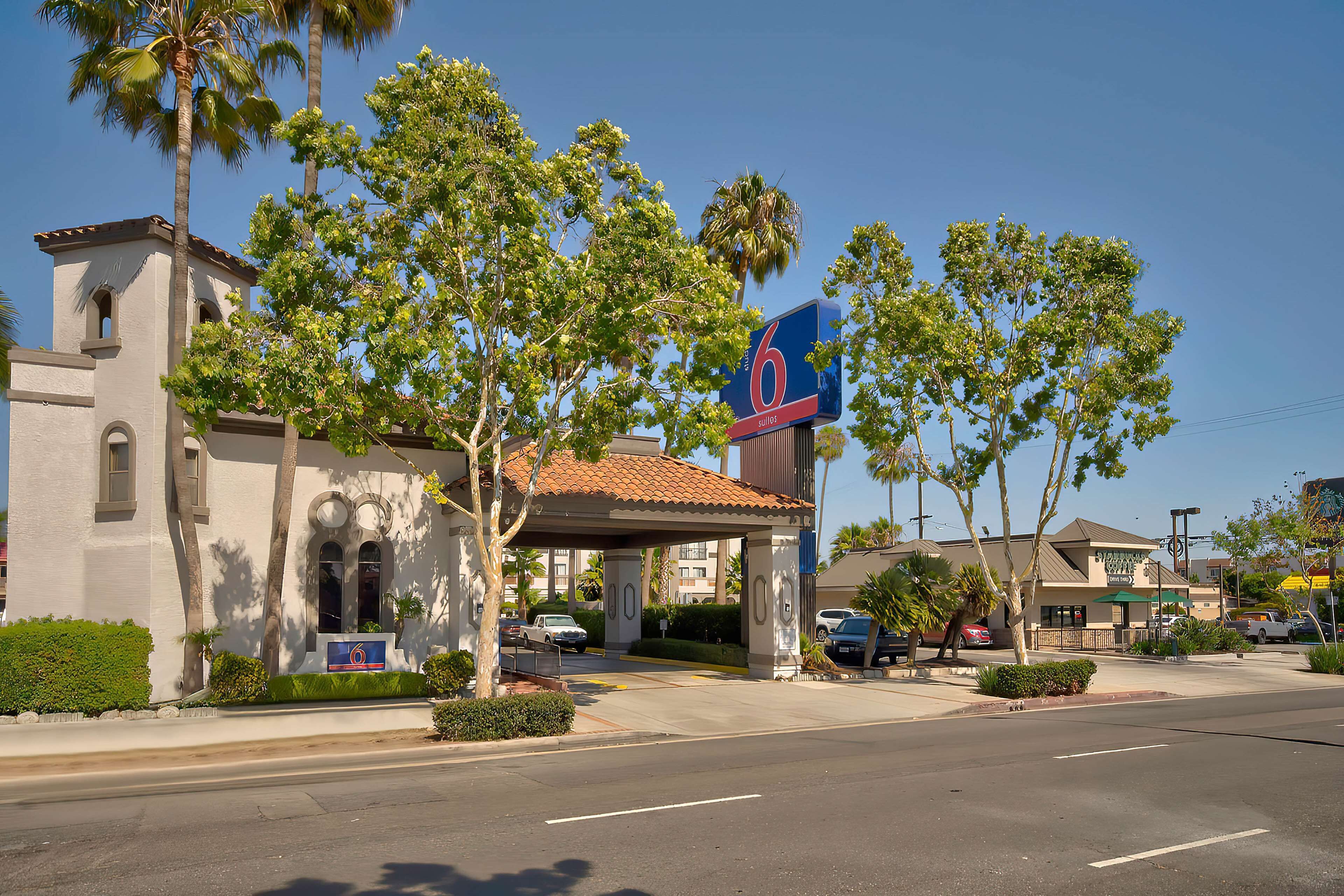 A motel with a large sign, palm trees, and a clear blue sky.