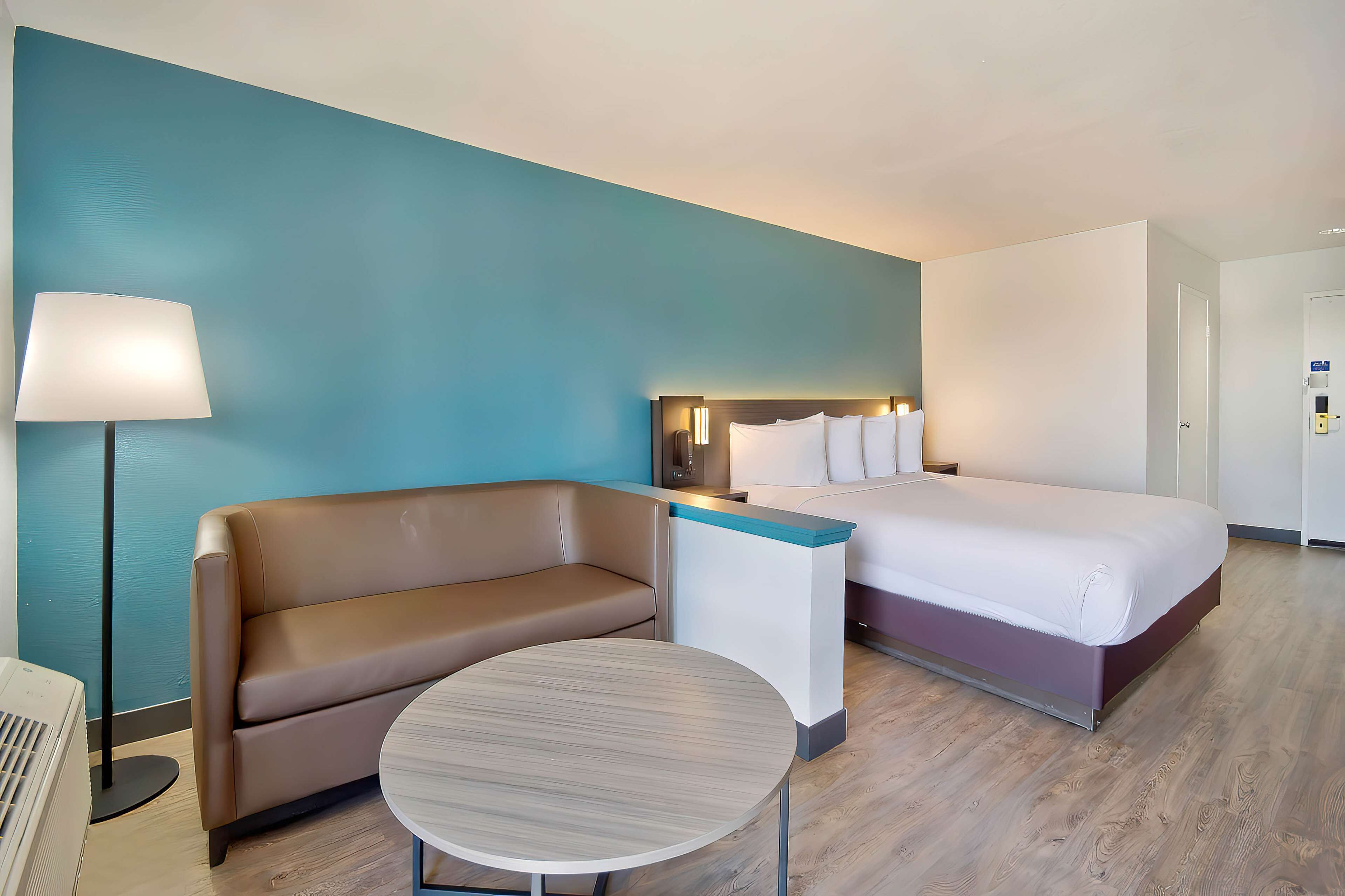 Een hotelkamer met een bed, een bank, een tafel en een lamp.