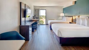 A hotel room with a bed, a desk, a TV, and a view of the outdoors. - Studio 6 Suites Lawndale, CA – South Bay (Lawndale)
