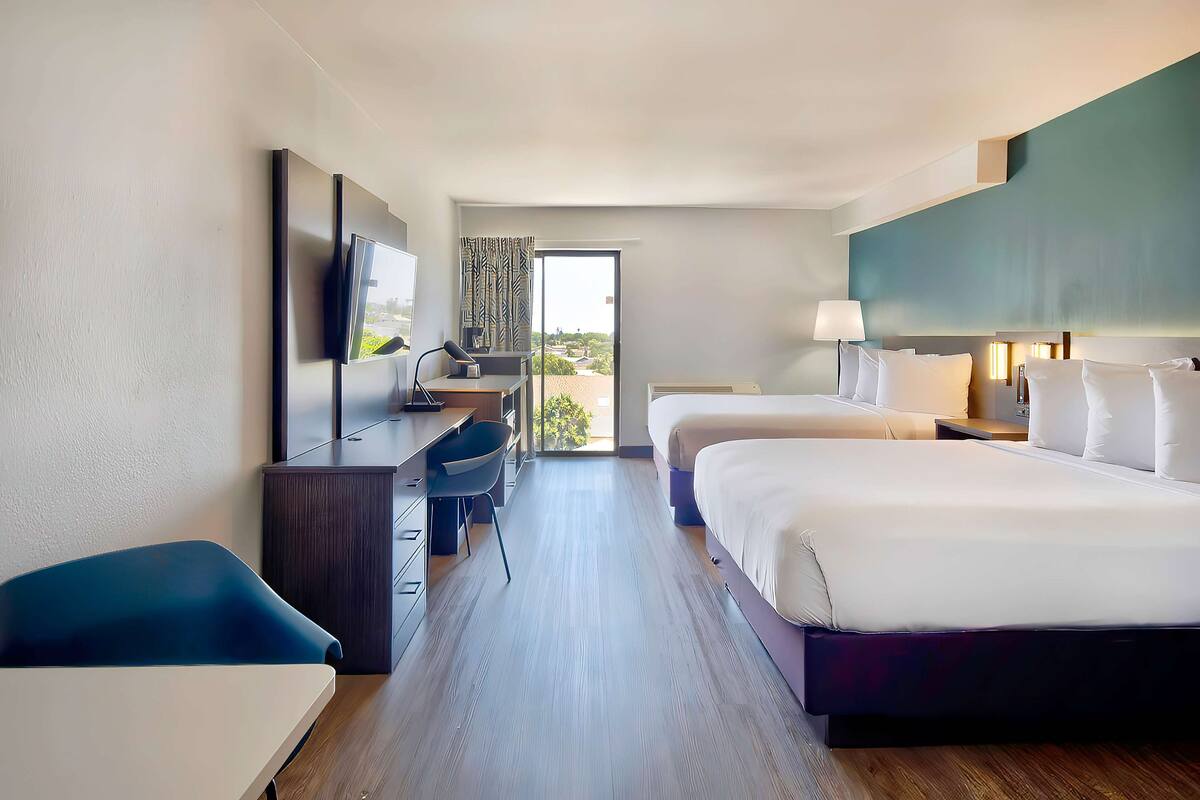 Ein Hotelzimmer mit Bett, Schreibtisch, Fernseher und Blick ins Freie.