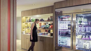 Une femme vêtue d’une robe noire et de talons hauts se tient devant une vitrine réfrigérée dans le hall d’un hôtel.