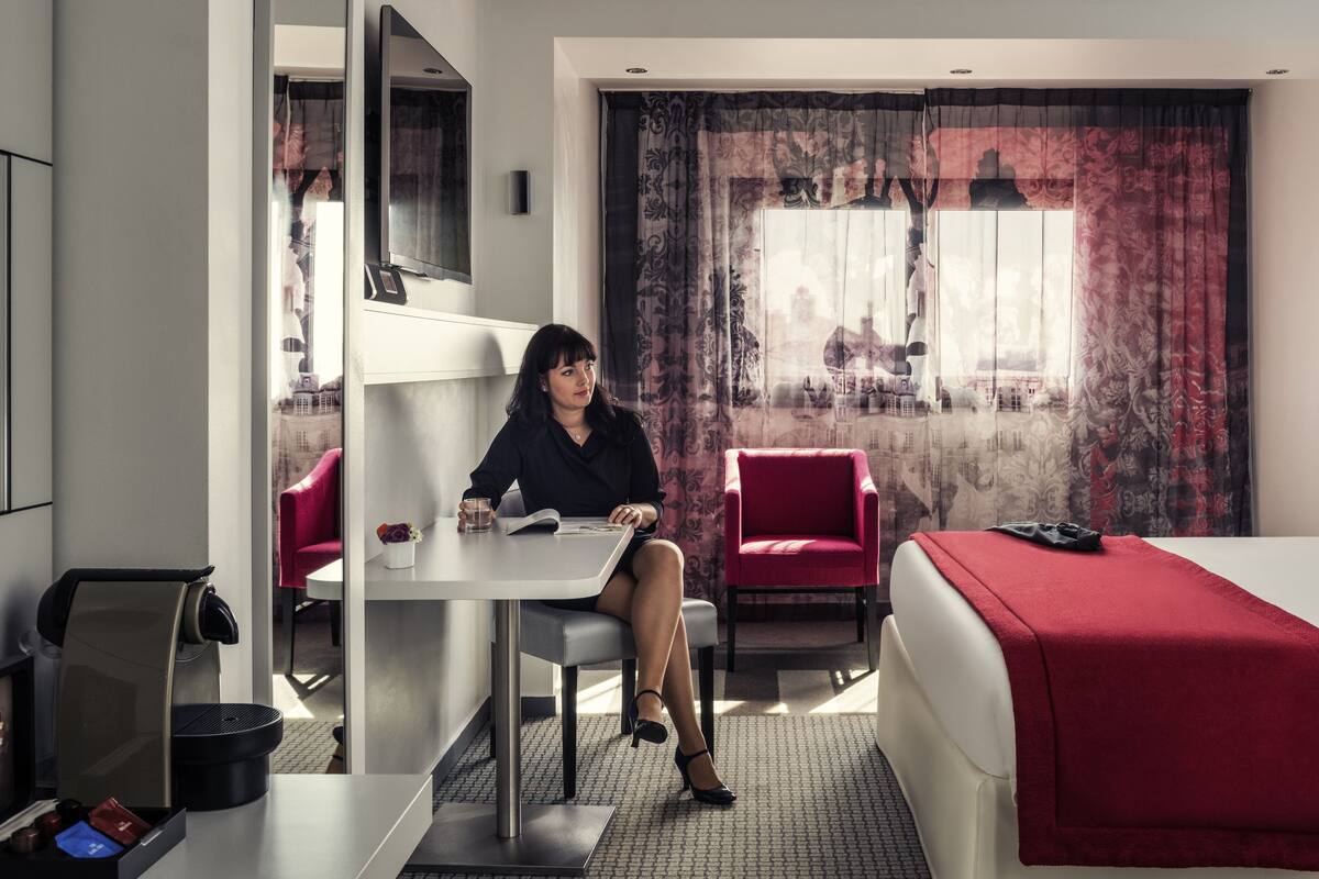 A hotel room with a bed, a desk, a chair, and a TV.