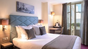 Une chambre d’hôtel avec un grand lit, un bureau, une chaise et une vue sur l’extérieur.