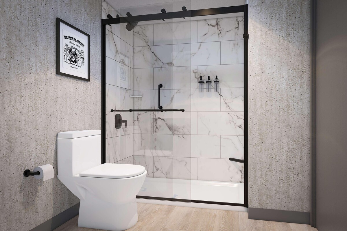 Un baño moderno con inodoro, ducha con puerta de cristal y pared de mármol.