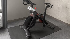 A stationary exercise bike with a control panel, a red handlebar, and a wall-mounted display. - DoubleTree by Hilton Dayton Fairborn (Fairborn)