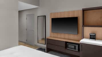 Habitación de hotel con cama, televisión, cafetera, microondas y armario.