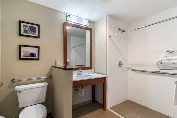 A bathroom with a toilet, sink, mirror, and shower.