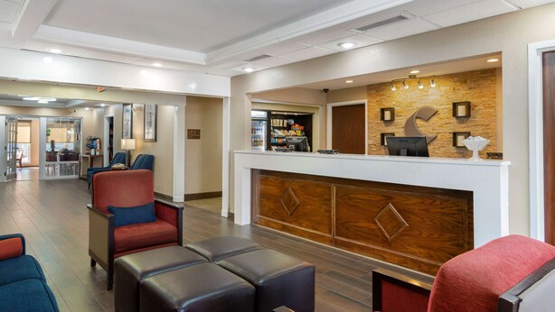 A hotel lobby with a reception desk, seating area, and a view into the dining area. - Comfort Inn & Suites - near Robins Air Force Base Main Gate (Warner Robins)