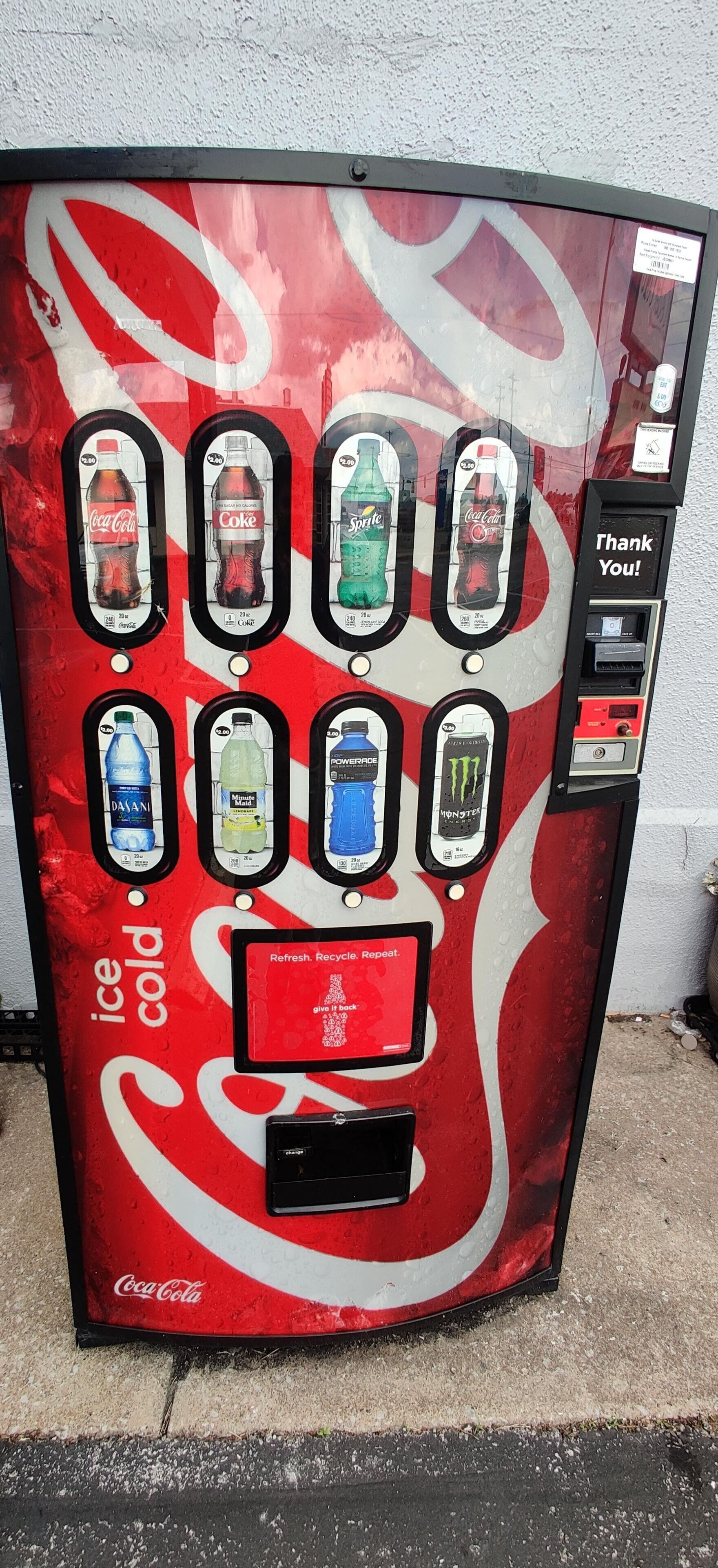 A Coca-Cola branded vending machine with multiple beverage options including Coca-Cola, Sprite, and Powerade.