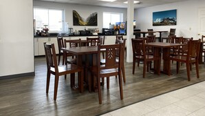A spacious dining area with wooden tables and chairs, a kitchen in the background, and artwork on the walls. - Cedar Cove (Sandusky)