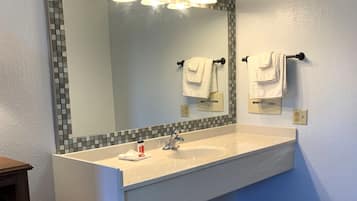 Un baño con un espejo grande, un lavamanos y un perchero para toallas.