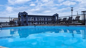 A swimming pool with lounge chairs and a building in the background. - Cedar Cove (Sandusky)