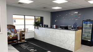 A reception area with a marble counter, a welcome sign, a plant, a computer, and a refrigerator. - Cedar Cove (Sandusky)