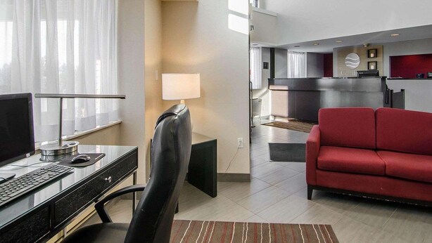 Una habitación de hotel con escritorio, computadora, silla y un sofá rojo.