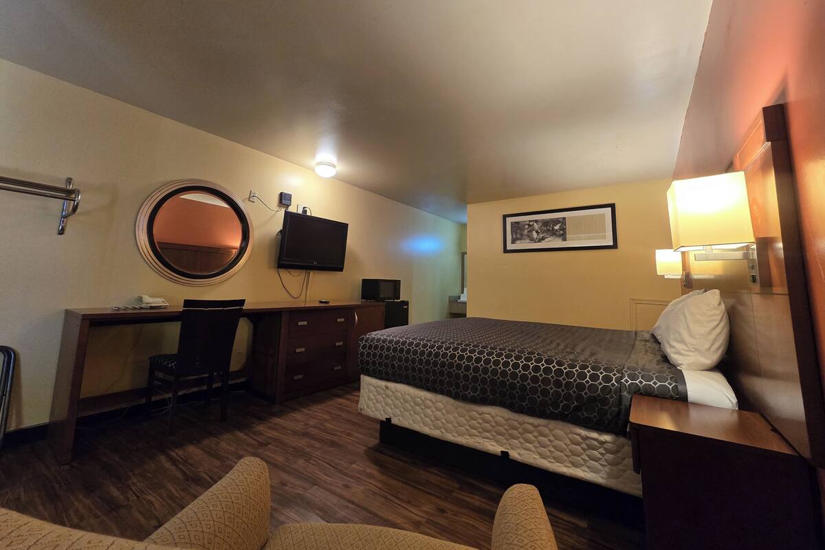 A hotel room with a bed, desk, chair, and a television.