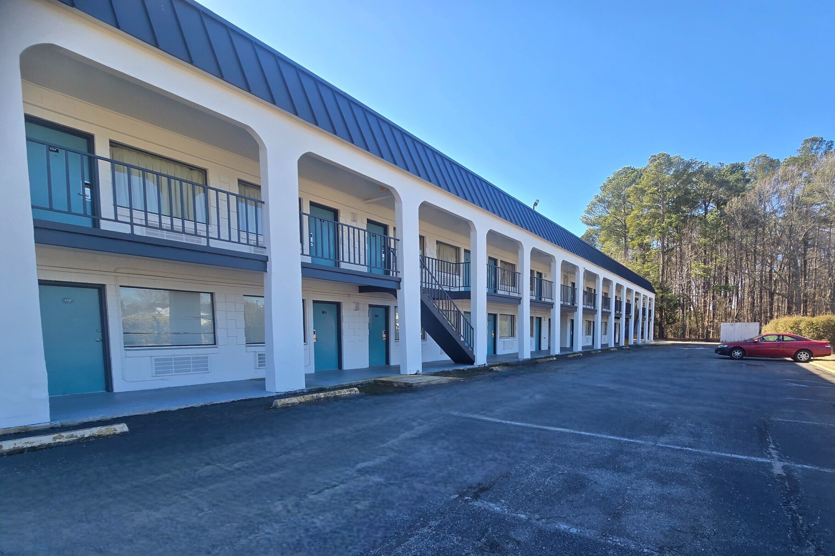 Un motel con una hilera de habitaciones, cada una con un balcón y una escalera que lleva al segundo piso.