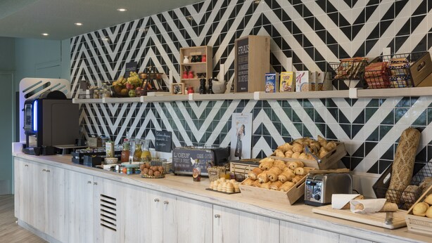 Una barra de desayuno con diversas opciones de comida, una máquina de café y un tostador.