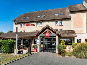 Ein Hotel mit auffälligem rotem Schild, überdachter Eingangspartei und gepflegtem Vorgarten.