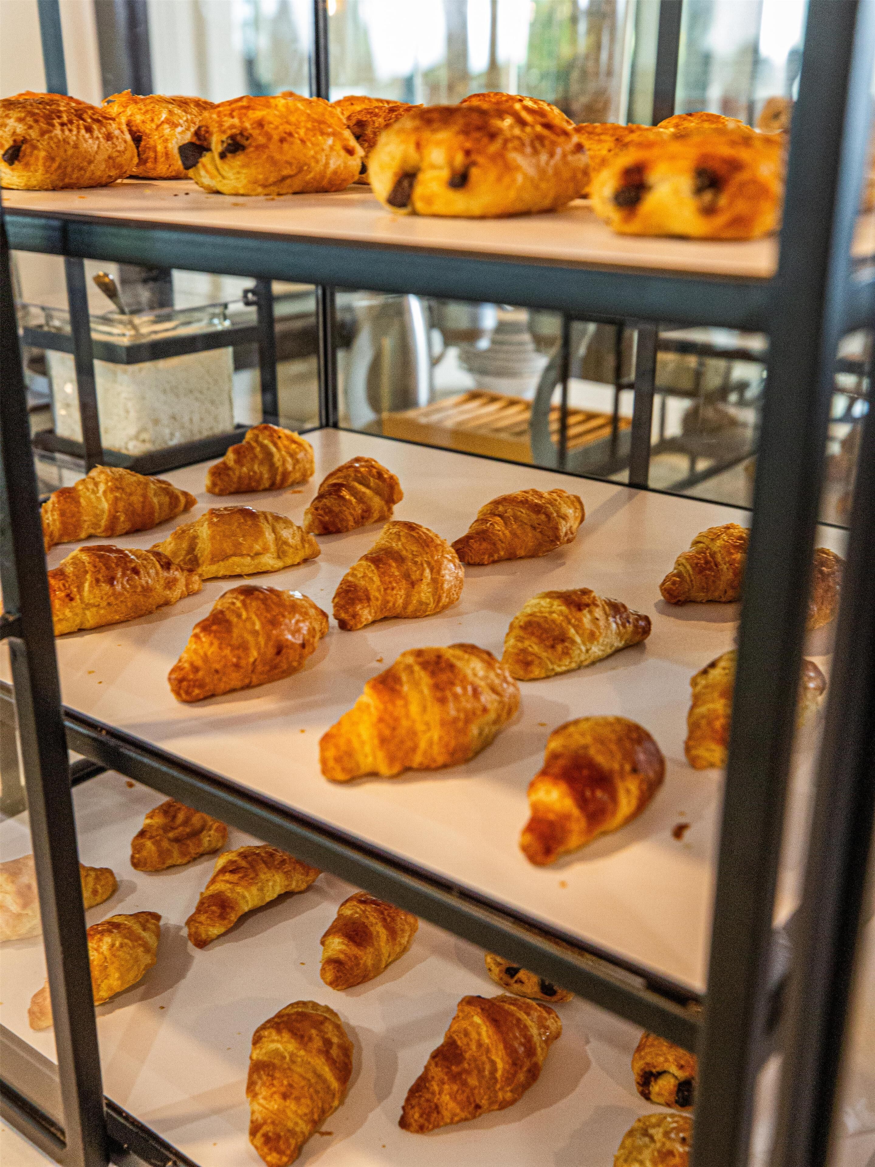 Una exhibición de cruasanes recién horneados en bandejas en una panadería.