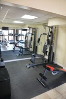 Un gimnasio con diferentes equipos de ejercicio, incluyendo cintas de correr, máquinas de pesas y una banca.