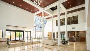 A spacious lobby with a high ceiling, large windows, and a central staircase.