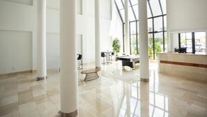 A spacious lobby with high ceilings, large windows, and a pool table.
