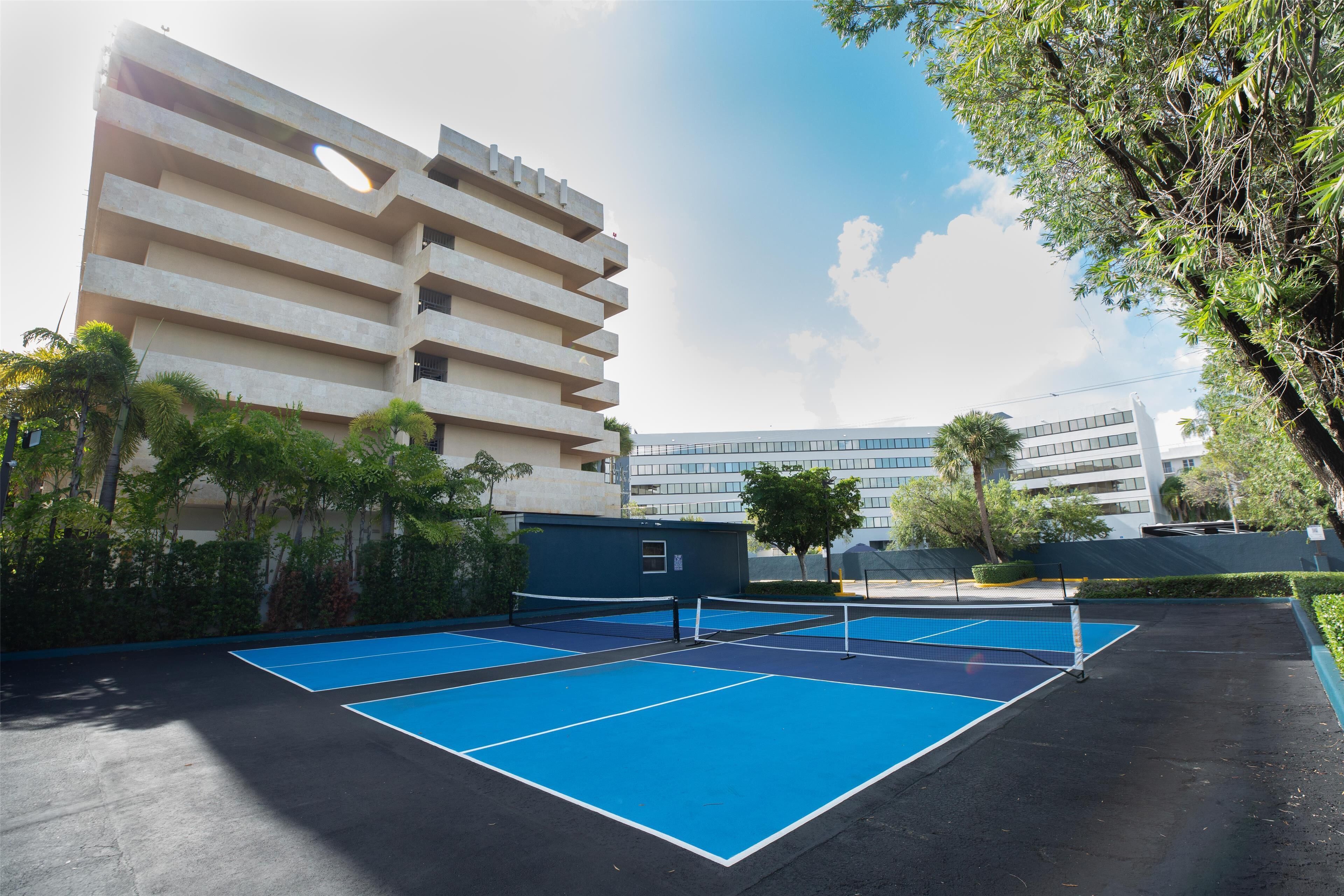 Una cancha de tenis al aire libre con un edificio al fondo.