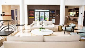 A modern lobby with a seating area, a refrigerator stocked with beverages, and a reception desk.