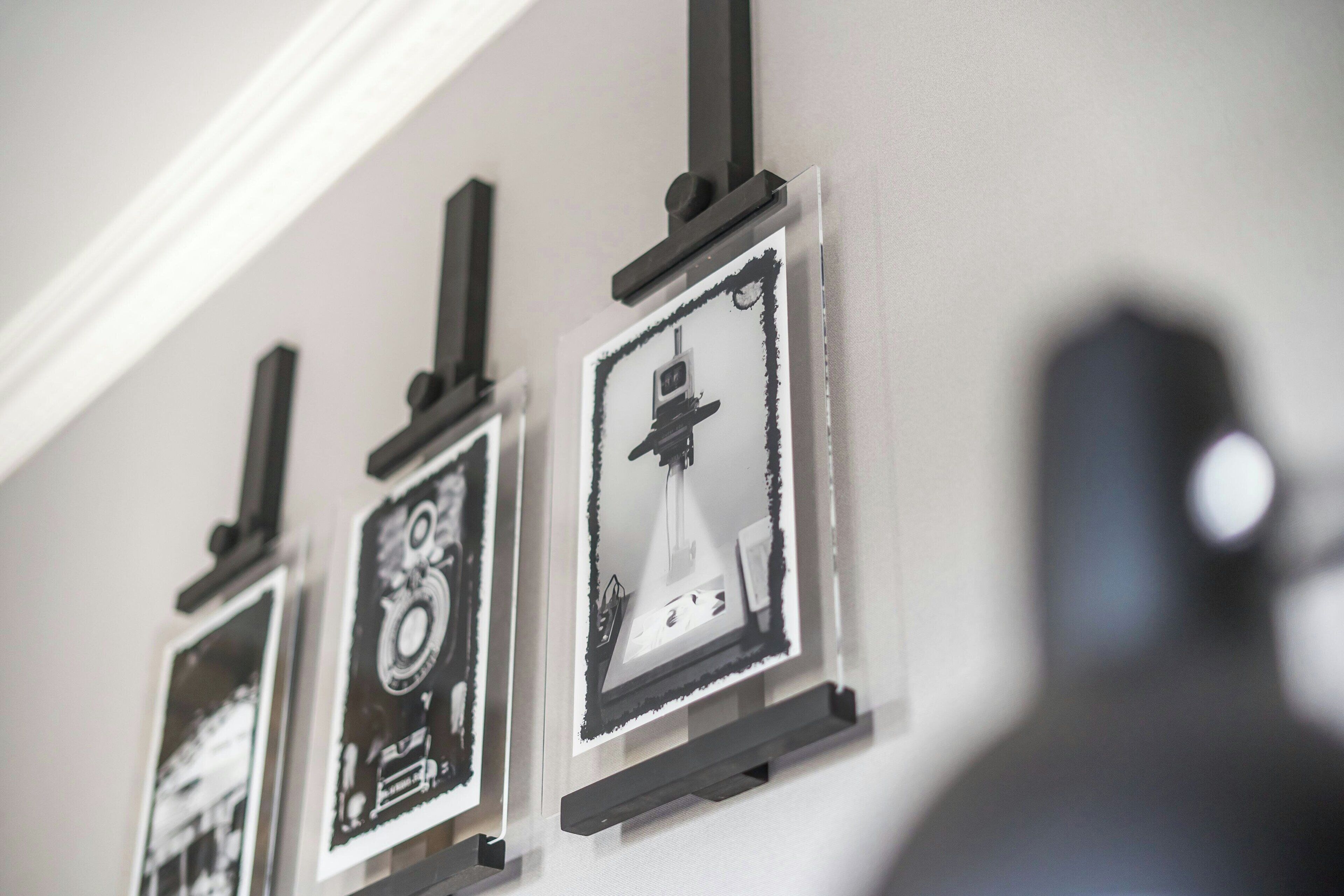 Eine Reihe von gerahmten Schwarz-Weiß-Fotos an einer Wand, jedes auf einer schwarzen Halterung befestigt.