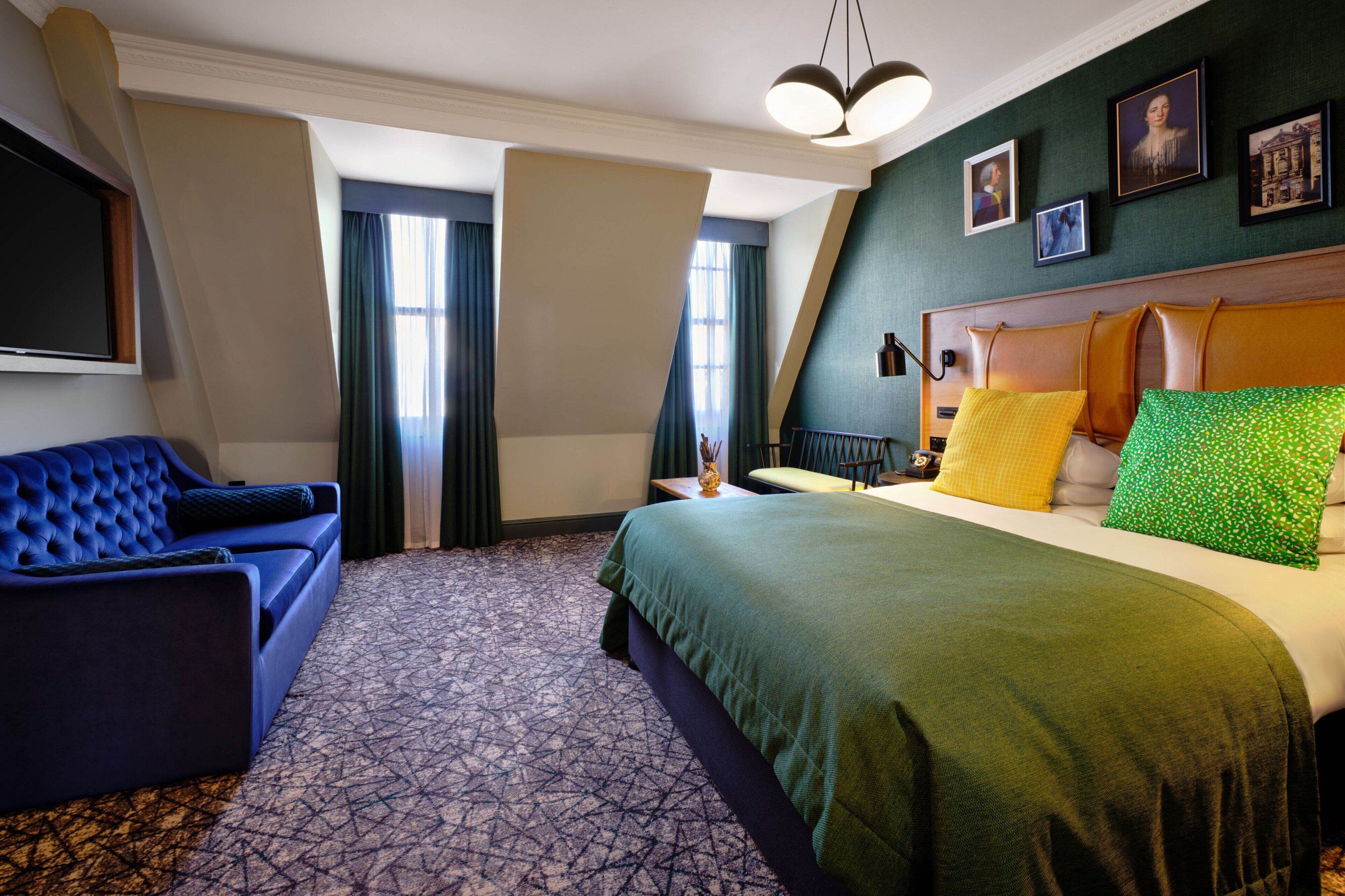 Een hotelkamer met een groot bed, een blauwe bank, een bureau en een televisie.