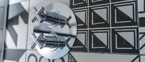 A close-up of a wall with geometric tile patterns and two metallic fixtures.