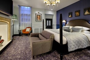 Una camera d'albergo con un letto grande, una sedia, un televisore e opere d'arte alle pareti.